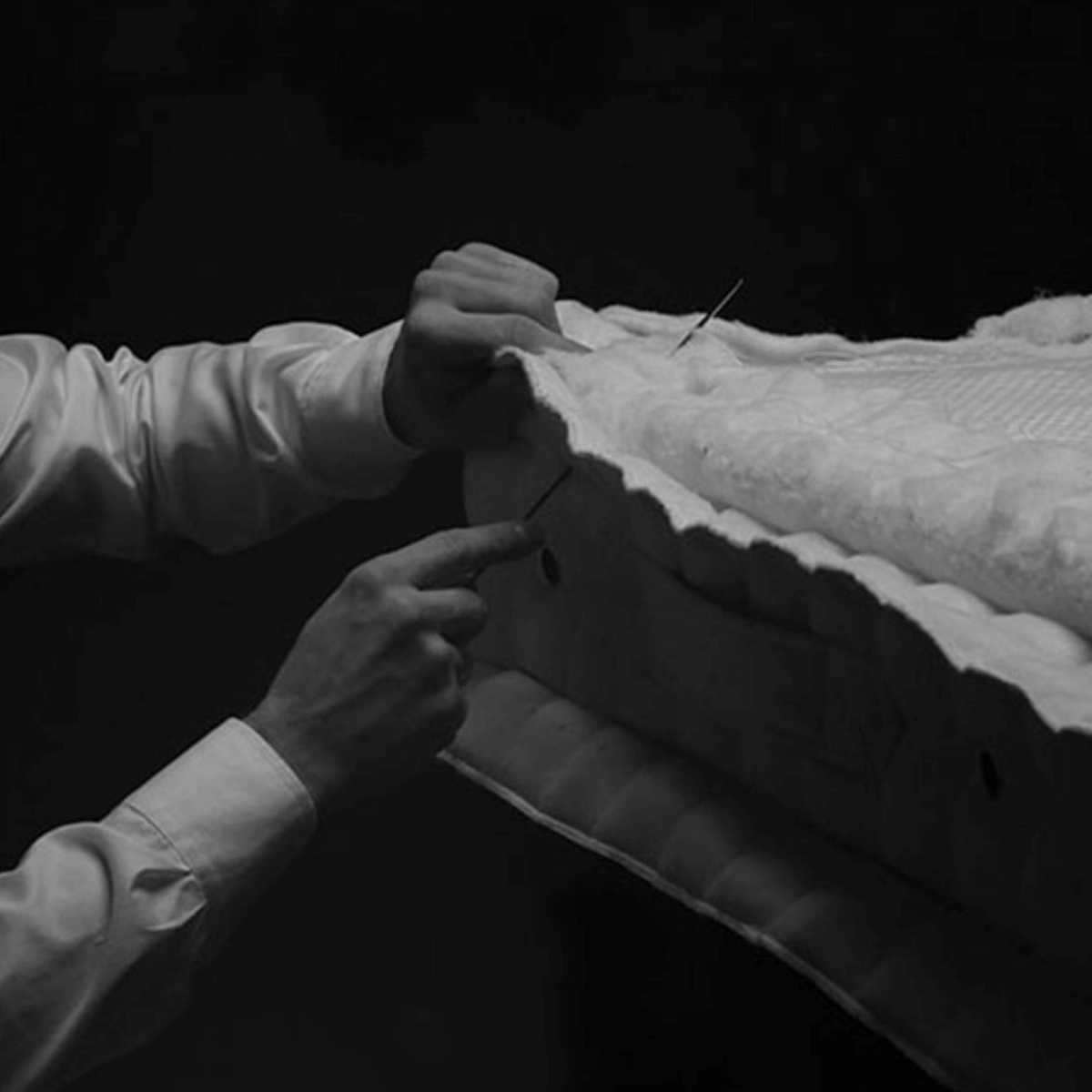 Craftsmanship in the English Royal Mattress, showcasing hands sewing high-quality natural fillers.