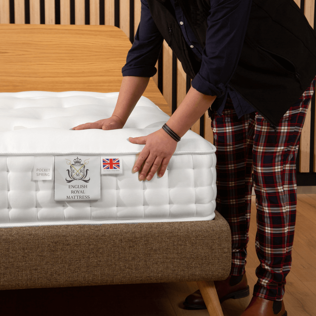 Person adjusting an English Royal Mattress with natural fillers and pocket springs on a wooden bed frame