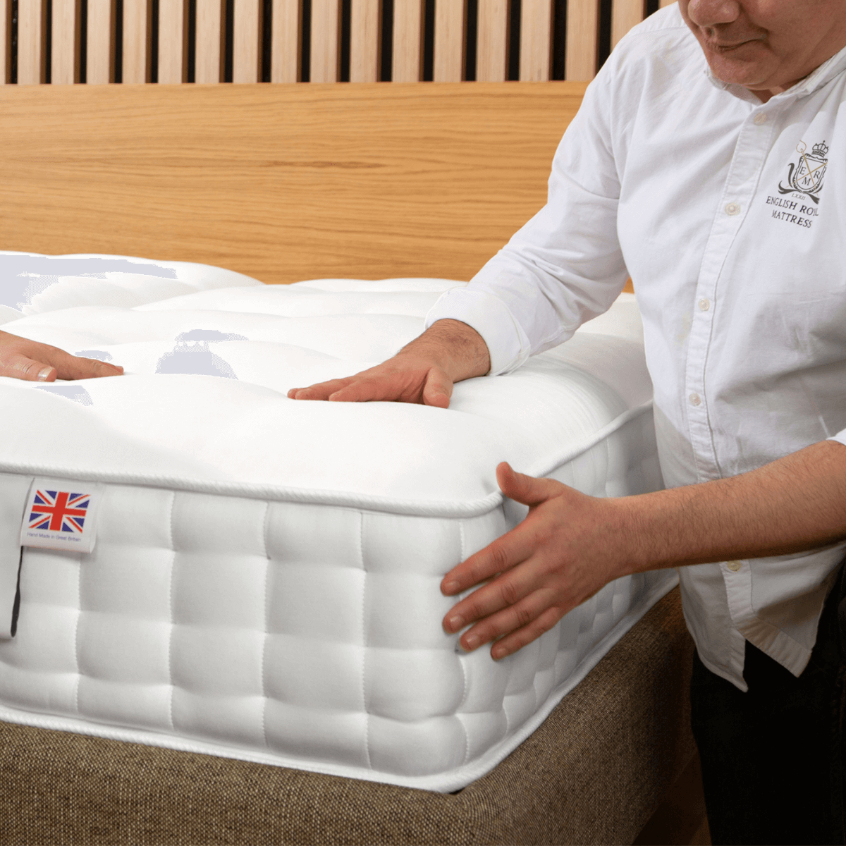 British craftsman adjusting a hand-made English Royal Mattress with natural fillers, showcasing quality and comfort.